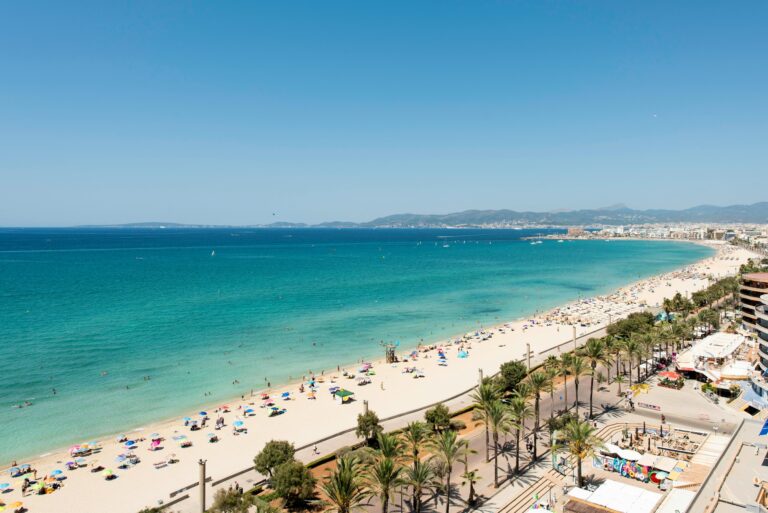 Vista panorâmica da Praia de Palma de Maiorca, com águas cristalinas e areia dourada, rodeada de restaurantes e hotéis perto da capital.